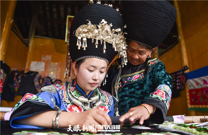 在贵州省铜仁市松桃苗族自治县太平营街道老寨村，一老人在指导绣娘绣苗绣。.jpg