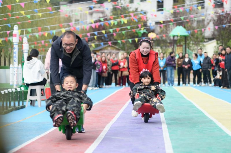931250-2025年11月12日,黄平县新州镇第四幼儿园,家长与孩子在彩色跑道上开展趣味推车竞赛。.jpg