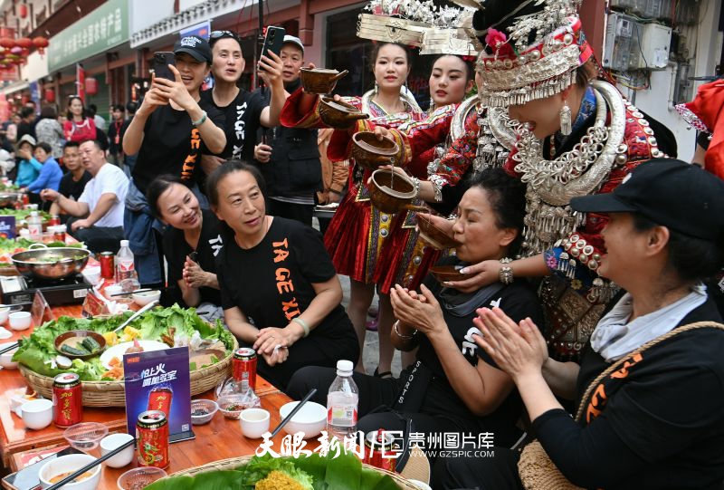 863630-2025年4月11日，贵州省黔东南苗族侗族自治州台江县姊妹街，苗族女青年在长桌宴上为游客敬“高山流水酒”。.jpg