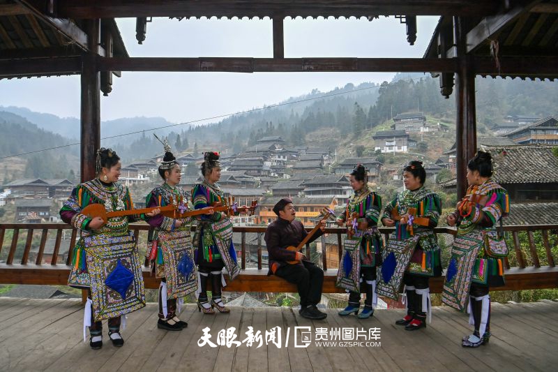 847219-2025年2月24日，贵州省黔东南苗族侗族自治州榕江县寨蒿镇晚寨侗寨，穿着侗族盛装的侗族女歌手在侗族琵琶歌传承人吴家文的带领下演唱侗族琵琶歌。.jpg
