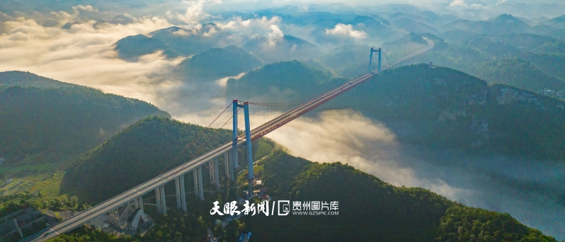 900997-图为近日，记者在凤冈县天桥镇河闪渡村拍摄的河闪渡乌江特大桥一景：河谷、晨务、青山、公路、民居与壮观的河闪渡悬索桥相映成景，如画交融。（饶云罗浪摄）.jpg