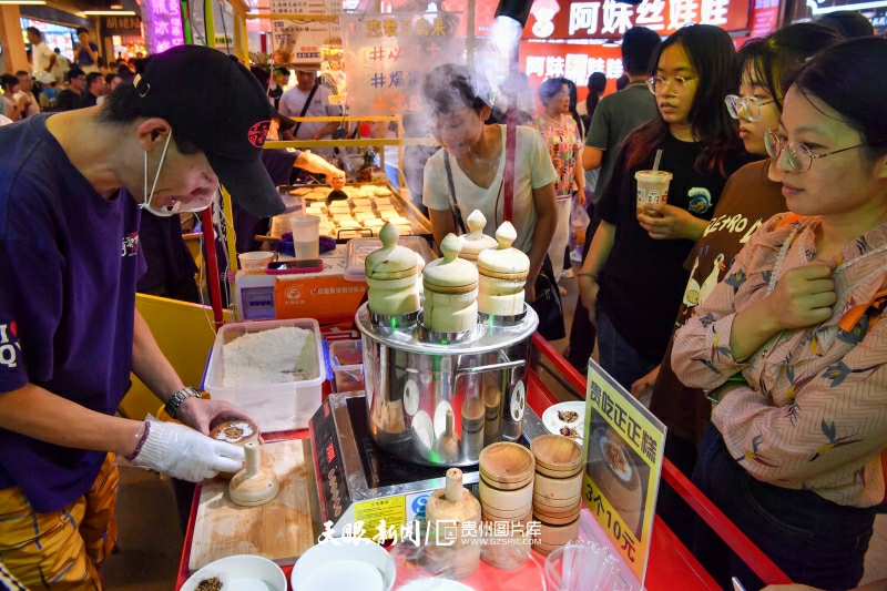 663533-2023年10月2日，夜幕下的贵州省贵阳市青云路青云市集特色美食区域，游客在排队购买正正糕。.jpg