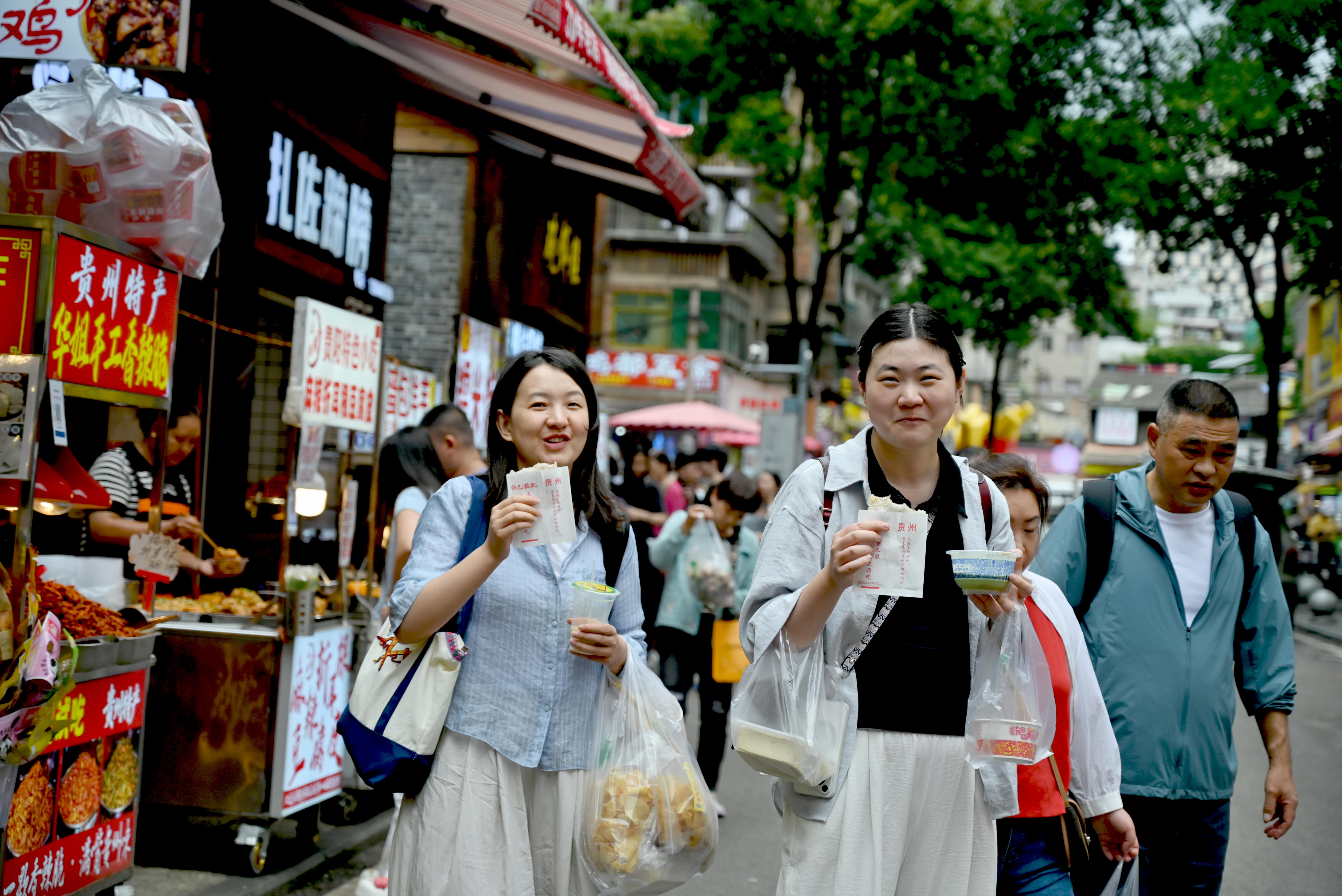 10月3日，贵阳市民生路街巷美食云集，游客手持本地风味小吃，乐享舌尖上的美味。本报记者 程洁 摄.jpg