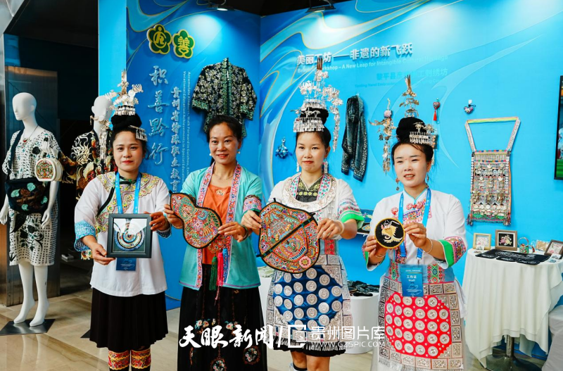 黎平县彦婷手工刺绣坊展览上，陆永江（左二）向嘉宾展示非遗刺绣.png